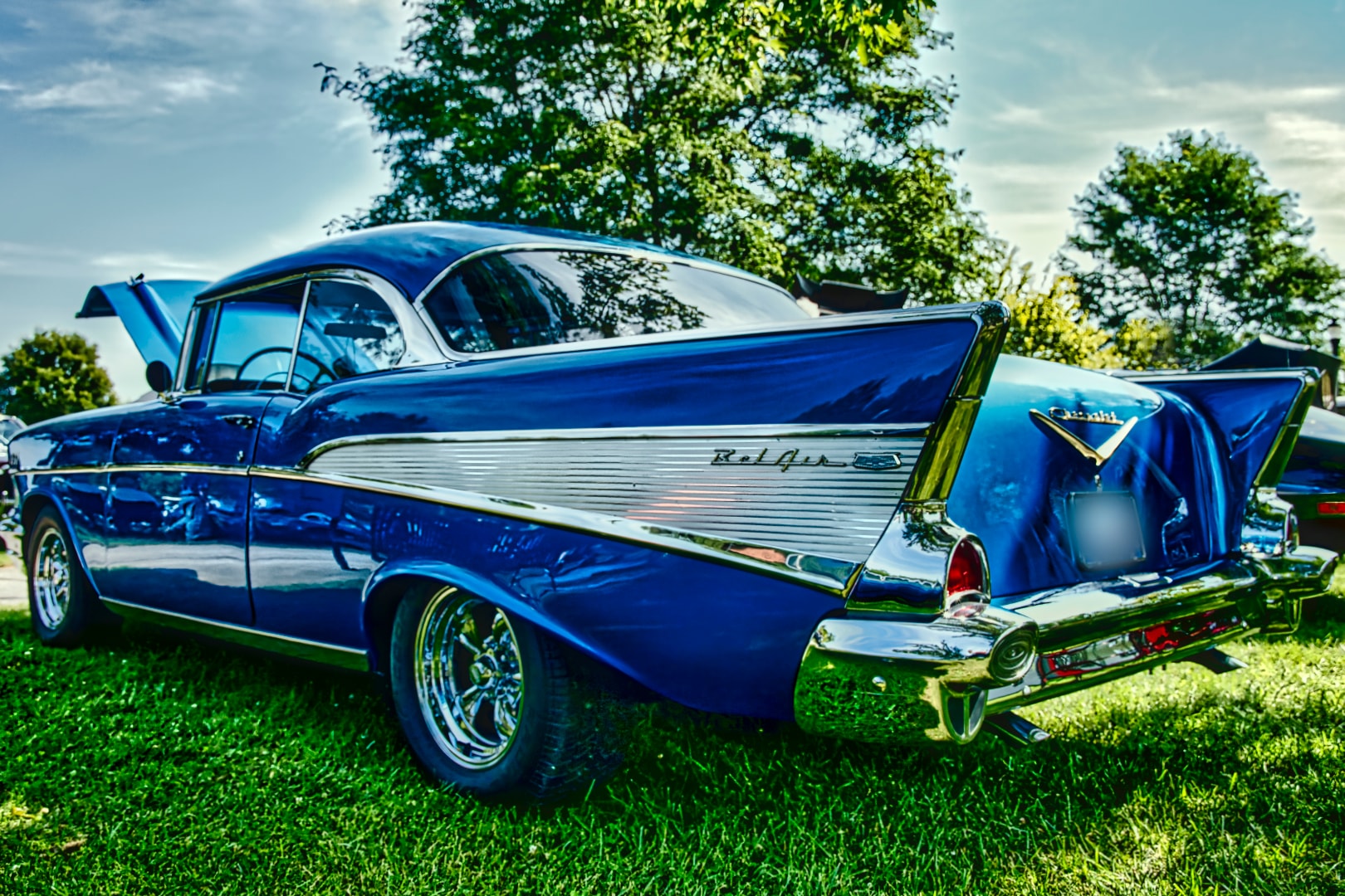1957 Chevrolet Bel Air in deep blue catching light along its fins at the auto show