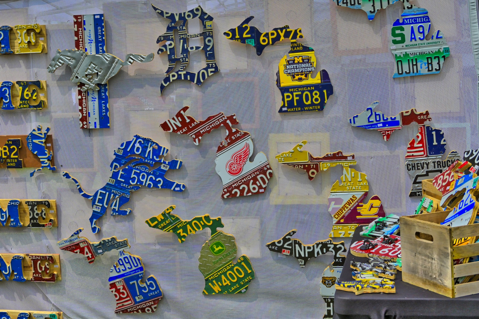 Michigan license plate art wall display featuring Lions, Red Wings, Tigers, and Pistons sports team designs at Blake's Lavender Festival vendor booth, Armada Michigan — event and product photography by Atelier Lens LLC