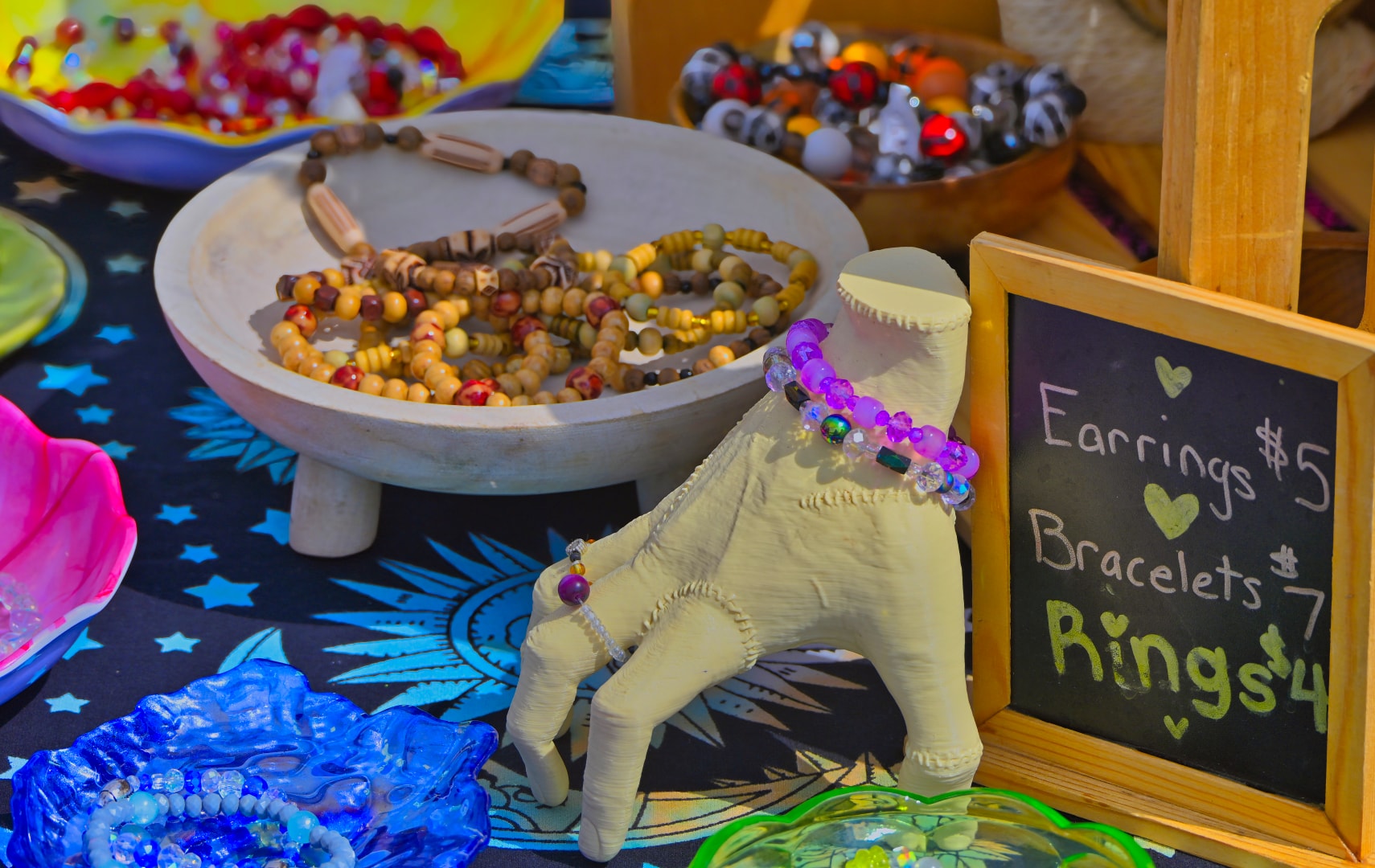 Handmade beaded jewelry display with earrings, bracelets, and rings at a vendor booth at Blake's Lavender Festival, Blake's Apple Orchard, Armada Michigan — festival product photography by Atelier Lens LLC