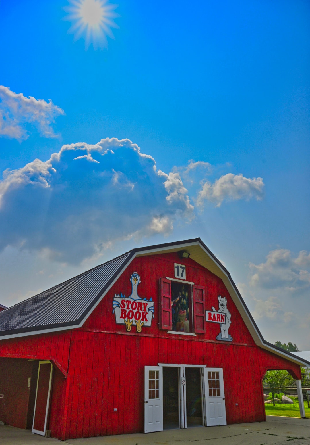 Story Book Barn at Blake's Apple Orchard — red gambrel barn with Story Book Barn signage, open loft doors, and a bright sunburst sky — commercial architecture photography, Armada, Michigan by Atelier Lens LLC